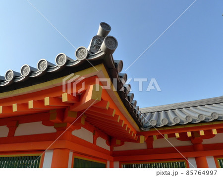雲一つない真っ青な空にそびえ立つ朱塗りの柱や梁、窓枠を持つ古代日本の建物、黒い屋根瓦と、青緑色の窓 85764997