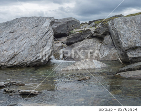 Water runs over the top of big grey stone boulders at water stream at arctic northern landscape in Swedish Lapland Water runs over the top of big grey stone boulders at water stream at arctic northern landscape in Swedish Lapland 85765854