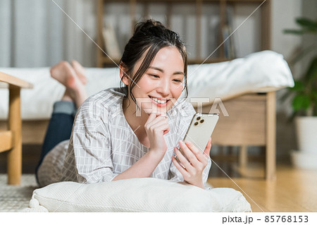 部屋でスマホを見る若い女性 85768153