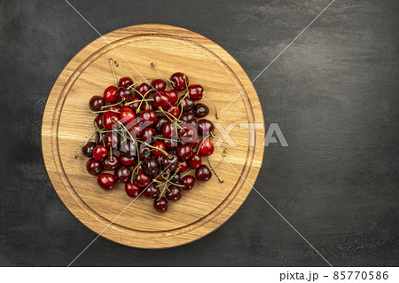 Fresh ripe sour cherries on wooden plate on gray background. Red juicy cherries. Sweet cherry background. 85770586