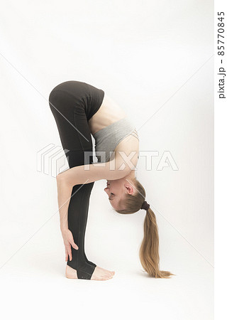 Portrait of gorgeous young woman practicing yoga. Flexible girl leaned at her feet. Gymnastics on white background. Yoga and Pilates. Vertical frame 85770845