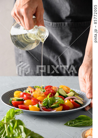 Woman cooking Panzanella salad from fresh vegetables. 85772005