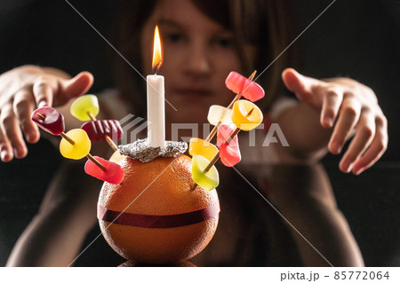 A little girl looks at the Orange Christingle she made. Selective focus. 85772064