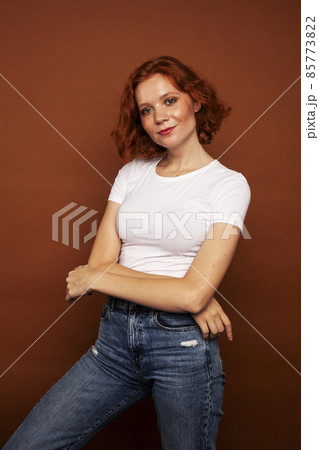 young pretty redhead girl posing cheerful on warm brown background, lifestyle people concept 85773822