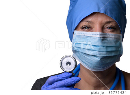 A female doctor in a medical mask and blue medical gloves holds a stethoscope  in her hands and looks at the camera 85775424