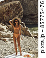 Beach Girl Model in Orange Bikini on the Rocky Deserted Seashore During Summer Beach Holidays 85775476