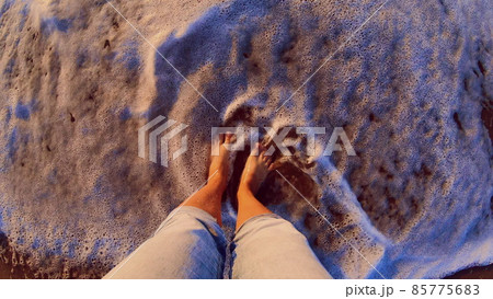Girl standing on sandy beach. Sea ocean wave with white foam rolls Girl standing on sandy beach. Sea ocean wave with white foam rolls 85775683