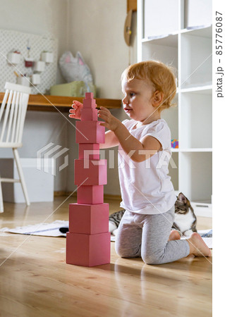 Cheerful toddler arrangement pink cubes assembling tower educational Maria Montessori materials Cheerful toddler arrangement pink cubes assembling tower educational Maria Montessori materials 85776087