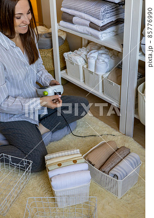 Woman neatly folded linens and towels use Marie Kondo method with sticky label tags 85776990