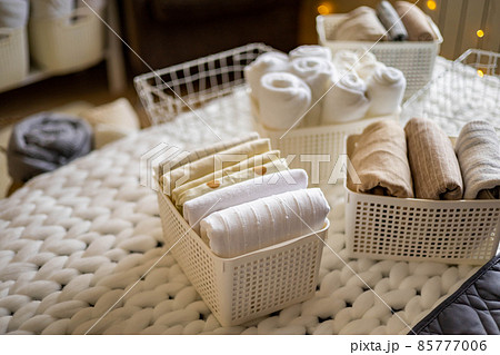 Modern housewife putting neatly folded towels, pillowcases, duvet covers into plastic metallic case 85777006