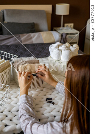 Woman hands neatly folded linens and towels use Marie Kondo method with sticky label tags 85777013