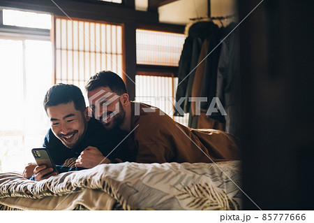 ベッドでスマホを見る同性愛カップル・LGBTQイメージ 85777666
