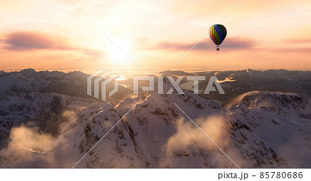 Dramatic Mountain Landscape covered in clouds and Hot Air Balloon Flying 85780686