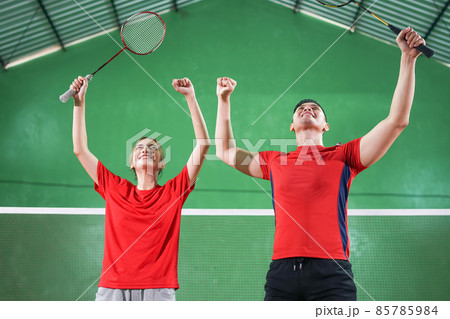 excited badminton players raise their hands on the court excited badminton players raise their hands on the court 85785984