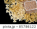 some dry wheat and different shapes of pasta standing on black background,close-up of macaroni and wheat together, 85786122