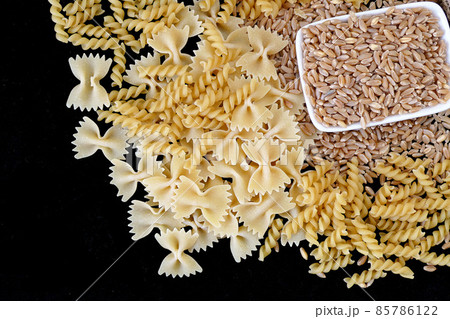 some dry wheat and different shapes of pasta standing on black background,close-up of macaroni and wheat together, 85786122