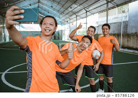 futsal players pose for selfies together using smartphone futsal players pose for selfies together using smartphone 85786126