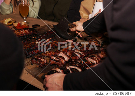 Waiter chops juicy barbecue ribs when serving to restaurant customers 85786987