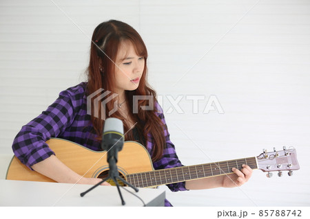 Girl singing on microphone and playing guitar Girl singing on microphone and playing guitar 85788742