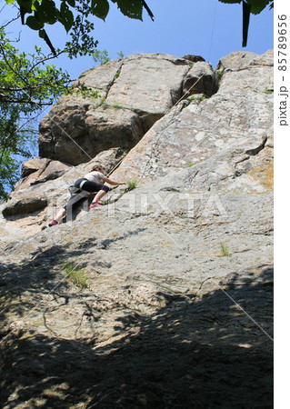 Woman rock climber climbs on a rock Woman rock climber climbs on a rock 85789656