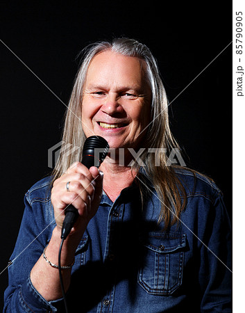 elderly man with long gray hair sings into a microphone 85790905