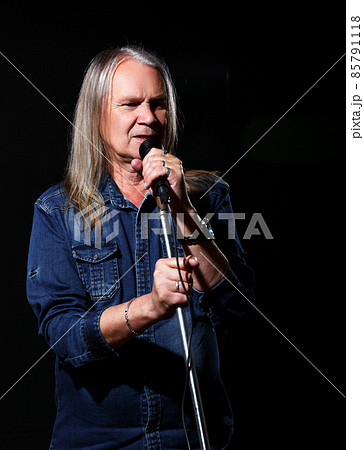 elderly man with long gray hair sings into a microphone 85791118