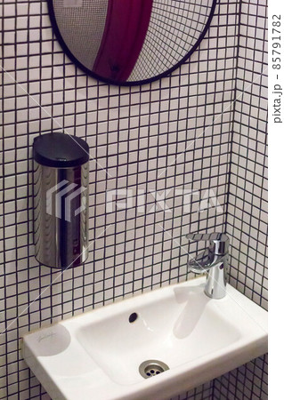 The interior of the toilet with white plumbing and small tiles 85791782
