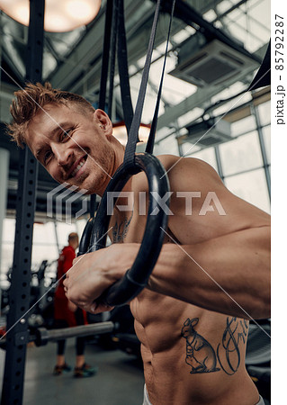 fitness, sport, bodybuilding and people concept - young man doing push-ups on gymnastic rings in gym. fitness, sport, bodybuilding and people concept - young man doing push-ups on gymnastic rings in gym. 85792287