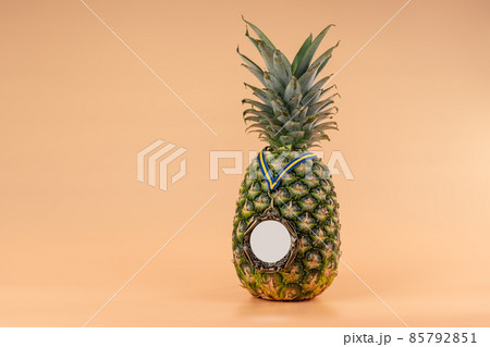 Interpretation of the pineapple fruit into a human image with a medal as a symbol of victory, success and strength. On a yellow background. Interpretation of the pineapple fruit into a human image with a medal as a symbol of victory, success and strength. On a yellow background. 85792851