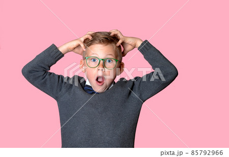 Amazed stressed kid boy in glasses and casual t-shirt with hands on head isolated on pink background. School child afraid or shocked. Surprised kid with fear and excited face. Good or bad news Amazed stressed kid boy in glasses and casual t-shirt with hands on head isolated on pink background. School child afraid or shocked. Surprised kid with fear and excited face. Good or bad news 85792966