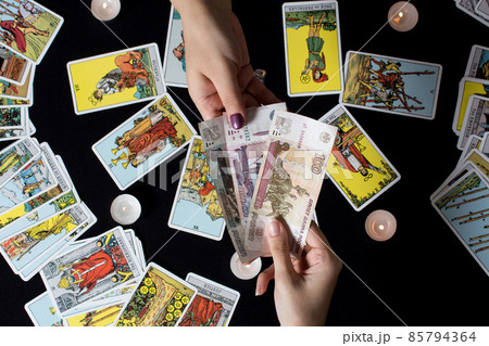Moscow,Russia November 22.19. Hands holding cash Rubles on the background of wallet and Tarot cards. Payment for esoteric, magical and witchcraft services in Russia is made in national currency rubles Moscow,Russia November 22.19. Hands holding cash Rubles on the background of wallet and Tarot cards. Payment for esoteric, magical and witchcraft services in Russia is made in national currency rubles 85794364