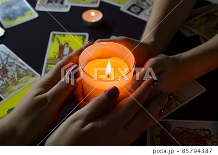Bangkok,Thailand,november.17.19. Night divination with candles. Seance and prediction of the future. Female hands hold a lighted candle in the dark at night. A fortune teller performs a magical ritual 85794387