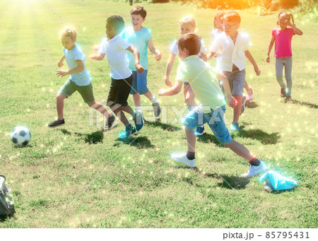 Cheerful children are jogning with ball on the playground. 85795431