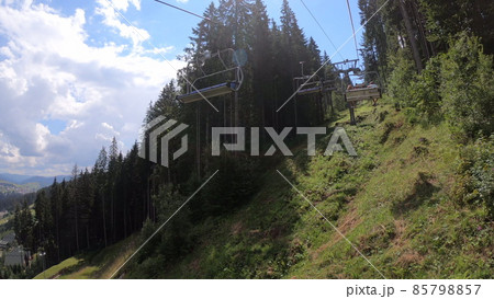 Ropeway with people movement in forest in mountains on sunny day. 85798857