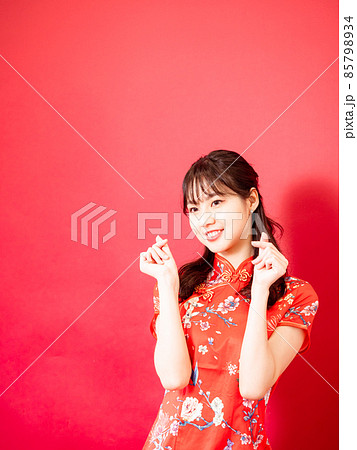 Young asian woman wear cheongsam showing mini heart sign isolated on red background. Young asian woman wear cheongsam showing mini heart sign isolated on red background. 85798934