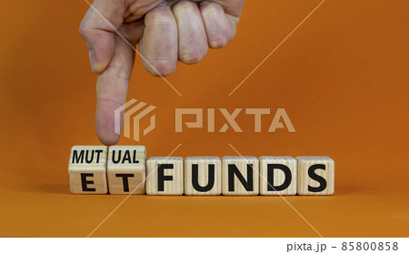 Mutual funds vs ETF symbol. Businessman turns a cube and changes words 'ETF, Exchange-Traded Fund' to 'Mutual funds. Beautiful orange background, copy space. Business and ETF vs mutual funds concept. 85800858