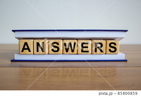 Concept word 'answers' on wooden cubes between pages of a book on a beautiful wooden table. White background. Business concept. Concept word 'answers' on wooden cubes between pages of a book on a beautiful wooden table. White background. Business concept. 85800859