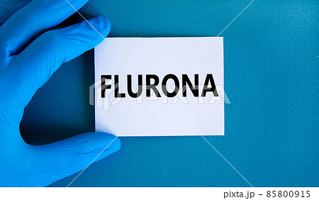 Covid-19 corona and flu flurona symbol. Hand in blue glove with white card. The concept word Flurona. Stethoscope. Medical and COVID-19 corona and flu flurona concept. Copy space. 85800915