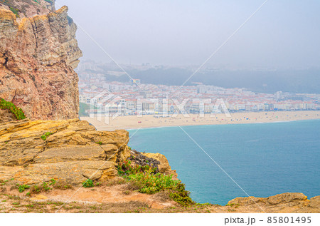 Aerial view of rocks and cliffs, azure turquoise water of Atlantic Ocean and sandy beach coastline Praia da Nazare Aerial view of rocks and cliffs, azure turquoise water of Atlantic Ocean and sandy beach coastline Praia da Nazare 85801495
