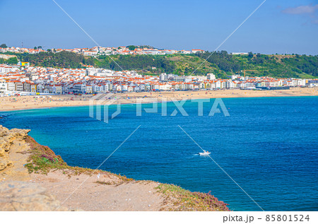 Aerial view of rocks and cliffs, azure turquoise water of Atlantic Ocean and sandy beach coastline Praia da Nazare Aerial view of rocks and cliffs, azure turquoise water of Atlantic Ocean and sandy beach coastline Praia da Nazare 85801524
