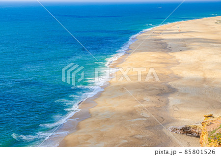 Top aerial panoramic view of sandy beach, waves of azure blue water of Atlantic Ocean and endless horizon near Nazare town Top aerial panoramic view of sandy beach, waves of azure blue water of Atlantic Ocean and endless horizon near Nazare town 85801526