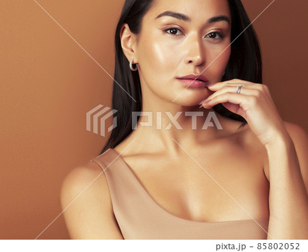 young pretty asian woman cheerful smiling posing on warm brown background, lifestyle people concept 85802052