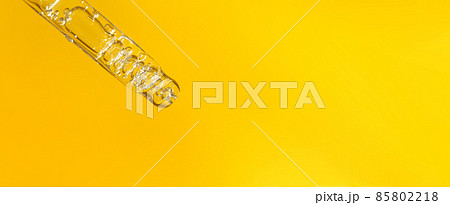 Banner of pipette with hyaluronic acid on yellow background. Cosmetics and healthcare concept closeup. Dose of serum or retinol with air bubbles. Flat lay. Luxury beauty product presentation in macro Banner of pipette with hyaluronic acid on yellow background. Cosmetics and healthcare concept closeup. Dose of serum or retinol with air bubbles. Flat lay. Luxury beauty product presentation in macro 85802218