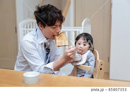 赤ちゃんに離乳食を食べさせる朝寝坊したパパ 赤ちゃんに離乳食を食べさせる朝寝坊したパパ 85807353