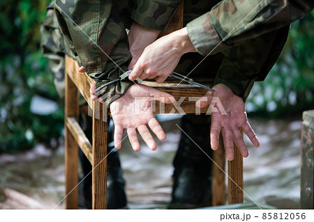 A woman puts handcuffs on a military suspect at the barracks. 85812056