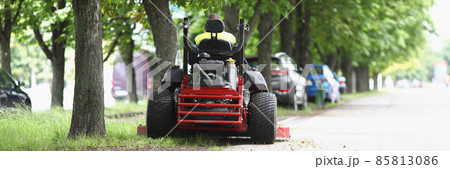 The lawn mower stands on sidewalk near the lawn 85813086