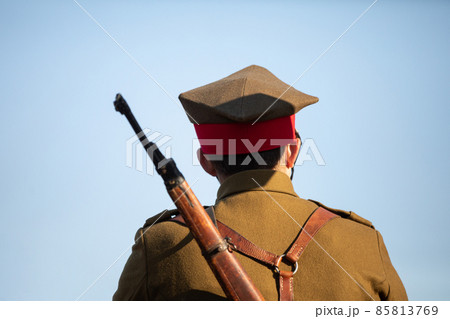 A soldier with a rifle on his back against a blue sky. 85813769