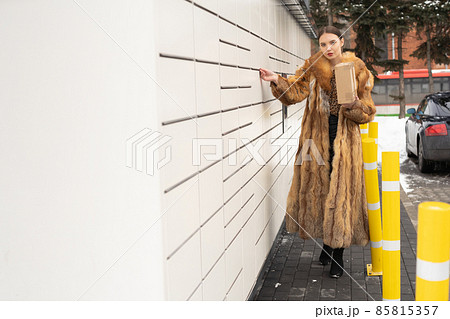 A rich woman cannot open a parcel locker box. Receive and send parcels automatically in winter. 85815357
