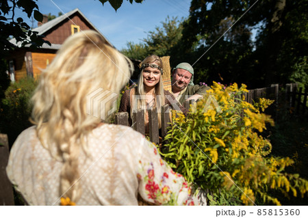 Neighbors cheerfully talking over the fence. A basket full of goldenrod herbs. 85815360