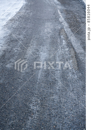 雪の日の塩化カルシウムが散布された道路 85816044